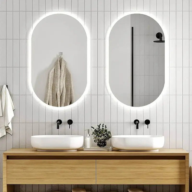Pair of pill oval LED mirrors with soft backlight in modern bathroom